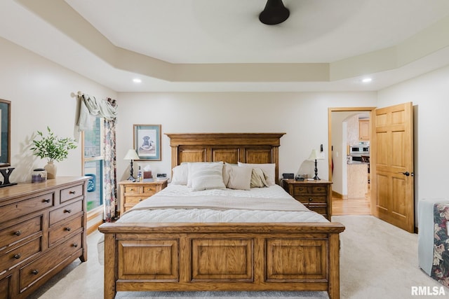 bedroom featuring recessed lighting, a tray ceiling, and light carpet