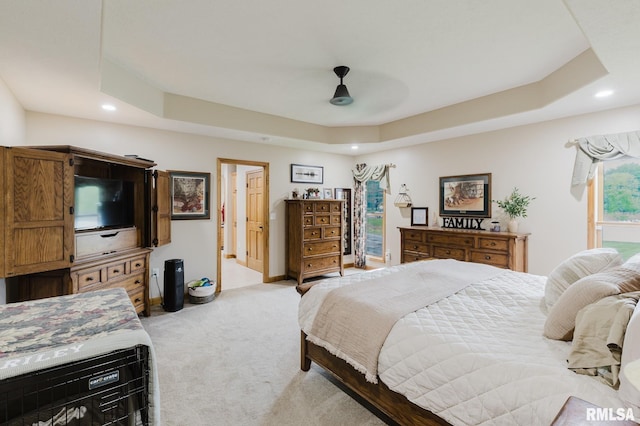 bedroom with light colored carpet, recessed lighting, and a raised ceiling