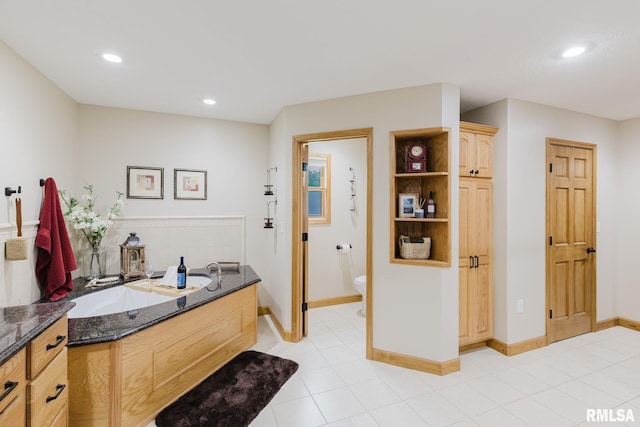 bathroom with toilet, baseboards, recessed lighting, and a garden tub