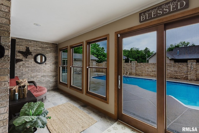 doorway to outside featuring baseboards and brick wall