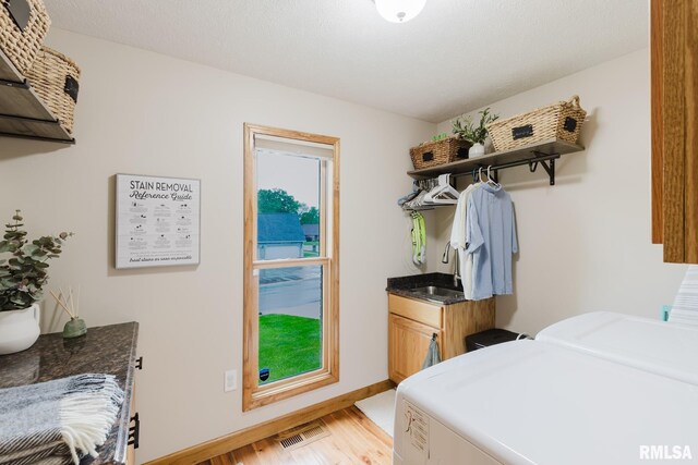 laundry room with independent washer and dryer, visible vents, light wood-type flooring, cabinet space, and a sink