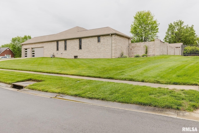 view of home's exterior with a lawn, an attached garage, and fence
