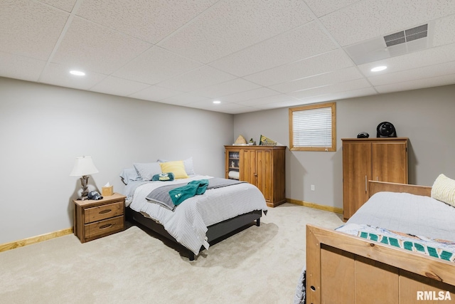 bedroom featuring light colored carpet, a drop ceiling, and visible vents
