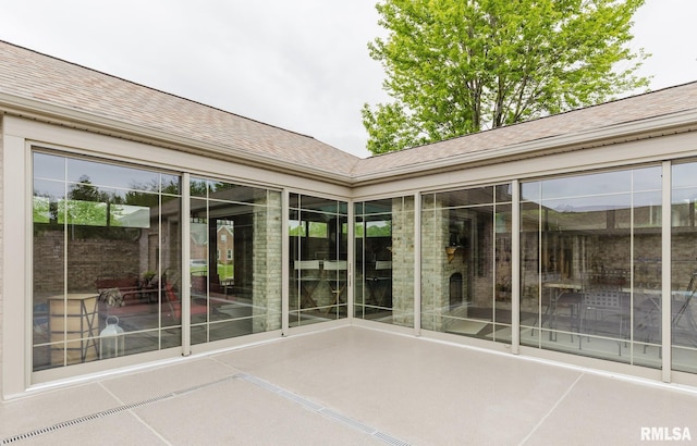 entrance to property with a patio and roof with shingles