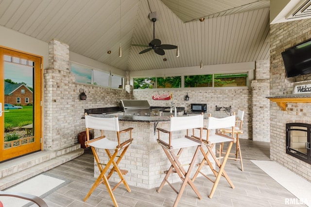 view of patio / terrace featuring a ceiling fan, exterior kitchen, grilling area, and a fireplace