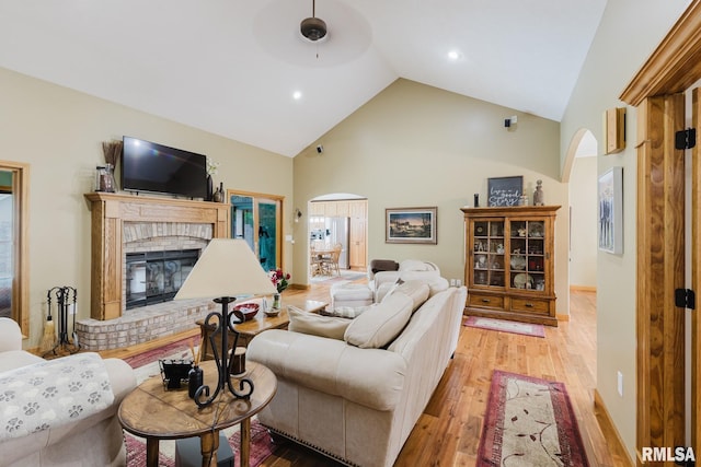 living room with a fireplace, hardwood / wood-style floors, high vaulted ceiling, recessed lighting, and arched walkways