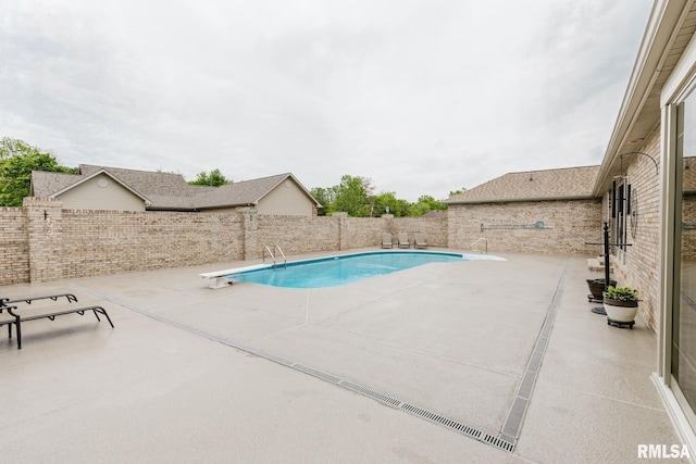 view of pool with a diving board, a fenced in pool, a fenced backyard, and a patio area
