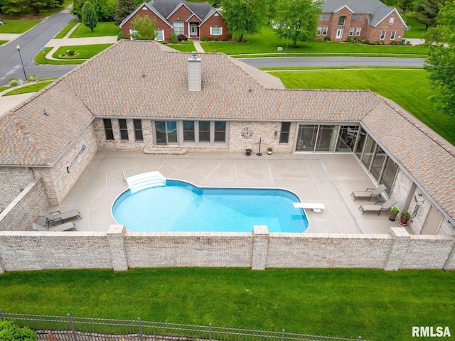 view of swimming pool featuring a patio, a diving board, a lawn, and fence