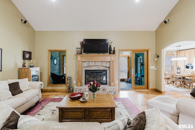 living area with light wood-style floors, a brick fireplace, and vaulted ceiling