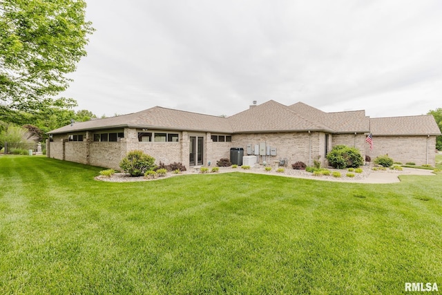 back of property with brick siding, a shingled roof, a lawn, and central air condition unit
