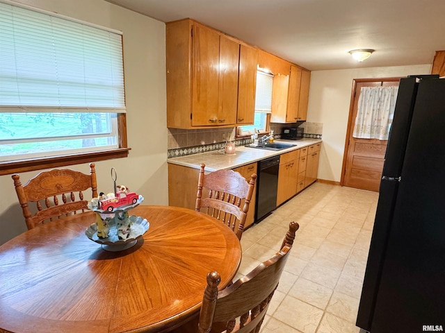 kitchen featuring tasteful backsplash, light countertops, light tile patterned floors, a sink, and black appliances