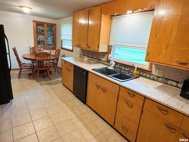 kitchen featuring tile countertops, a sink, black appliances, and tasteful backsplash