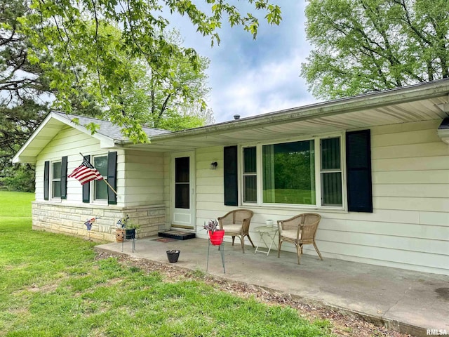 rear view of property with a lawn and stone siding