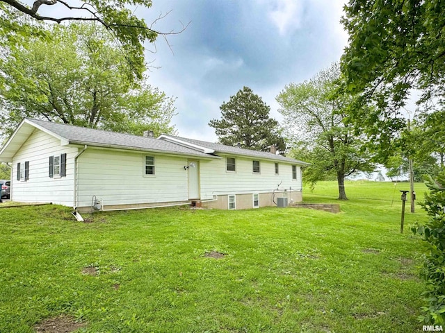 back of property featuring central air condition unit, a chimney, and a yard