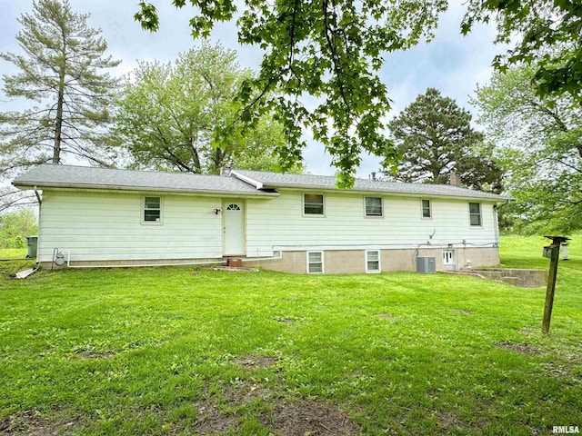 rear view of property with central air condition unit and a yard