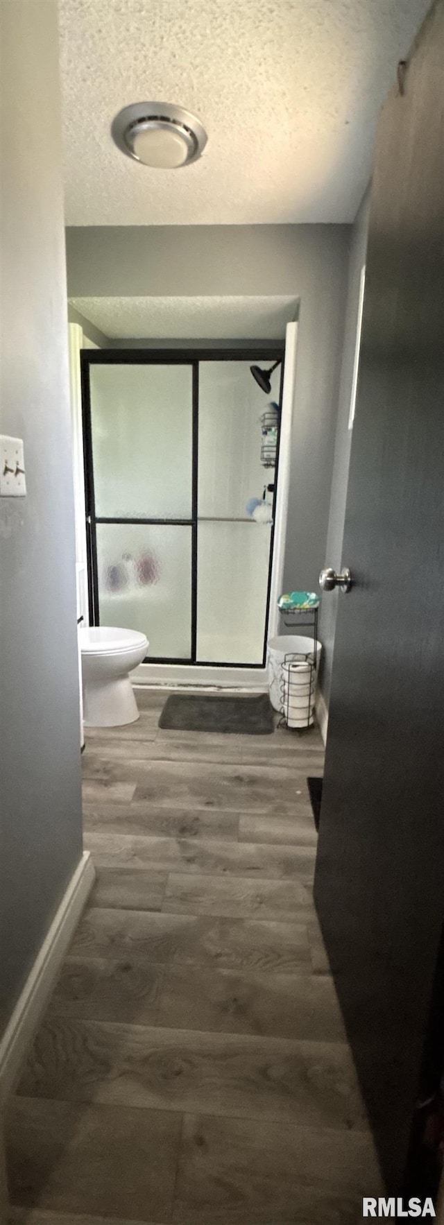bathroom featuring baseboards, a textured ceiling, toilet, and wood finished floors
