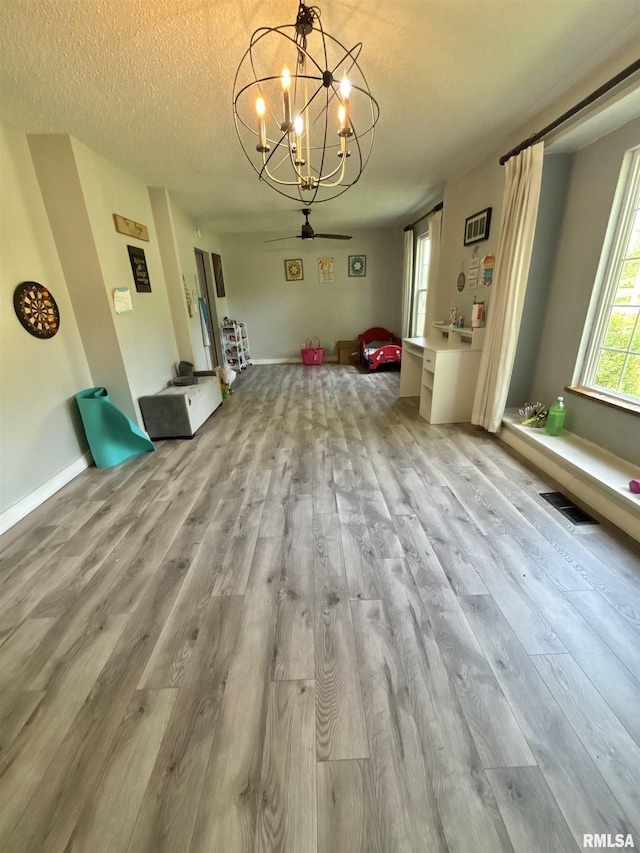 unfurnished dining area with visible vents, wood finished floors, and ceiling fan with notable chandelier