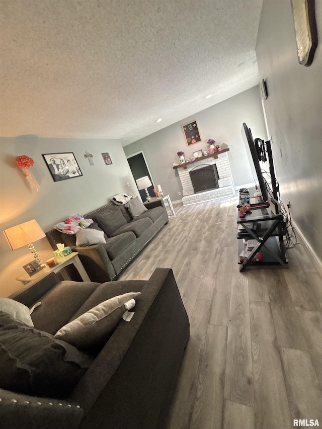 living room with baseboards, a textured ceiling, wood finished floors, and a fireplace