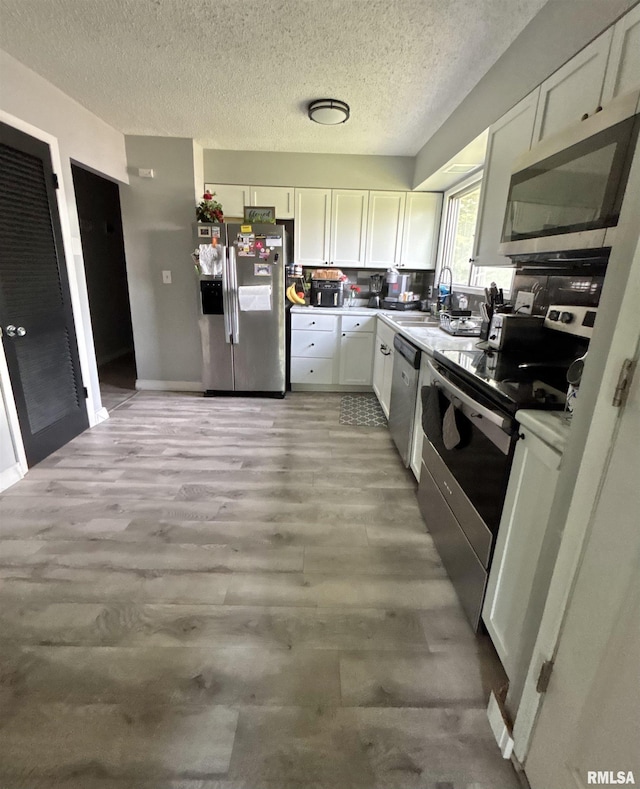 kitchen with light countertops, a textured ceiling, stainless steel appliances, and white cabinetry