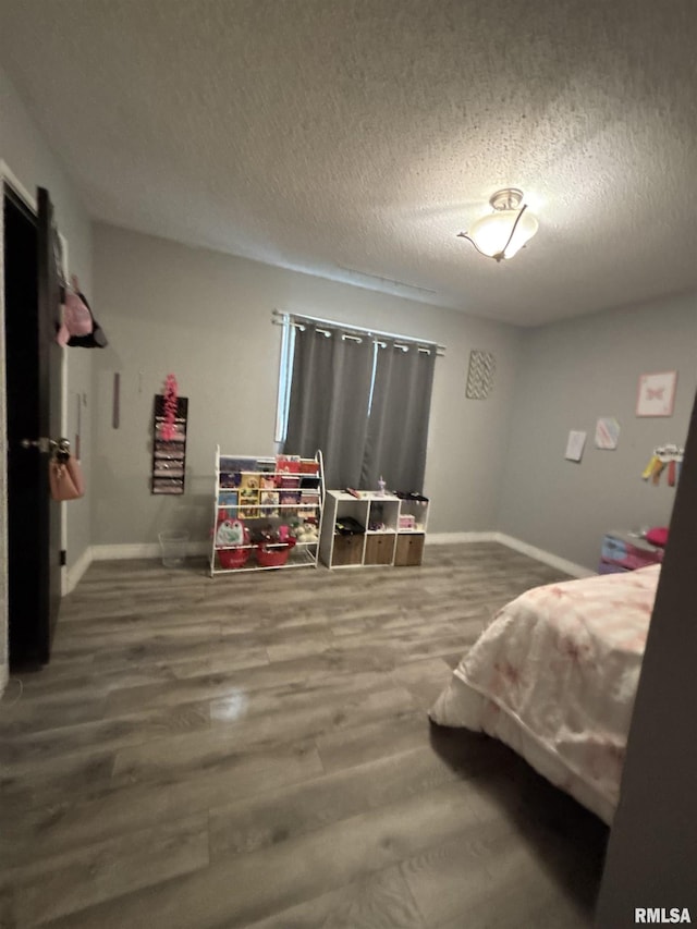 bedroom featuring baseboards, a textured ceiling, and wood finished floors