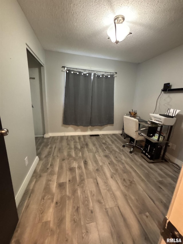 home office with baseboards, a textured ceiling, and wood finished floors