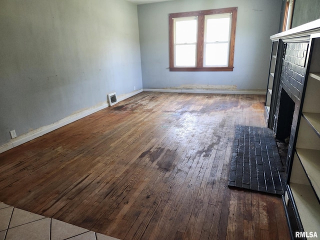 unfurnished living room with visible vents, wood-type flooring, baseboards, and a fireplace