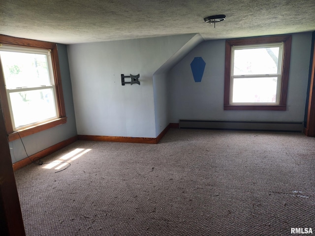 additional living space with plenty of natural light, a baseboard radiator, and a textured ceiling