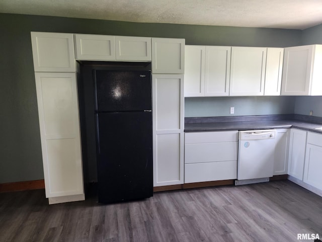 kitchen featuring freestanding refrigerator, wood finished floors, dark countertops, white dishwasher, and white cabinetry