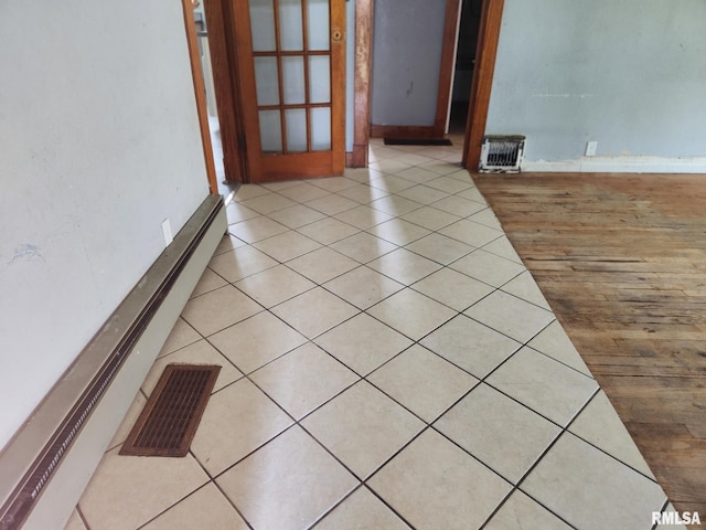 spare room with baseboard heating, baseboards, visible vents, and light tile patterned floors