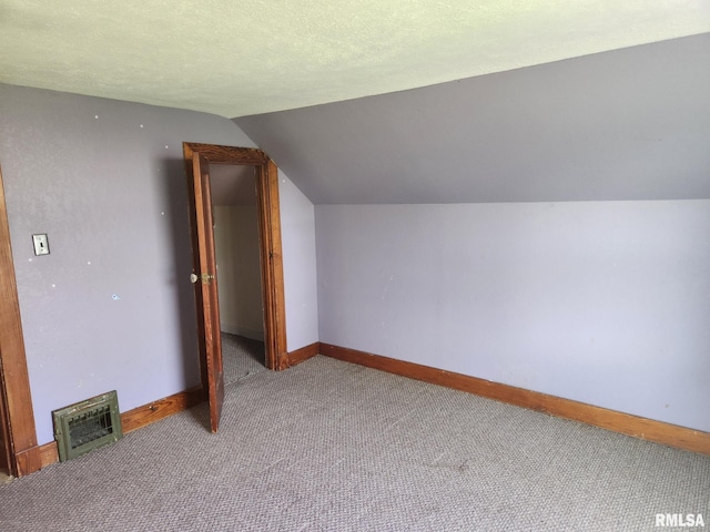 additional living space featuring carpet floors, baseboards, visible vents, and vaulted ceiling