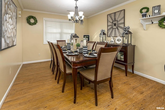 dining space with an inviting chandelier, light wood-type flooring, baseboards, and crown molding