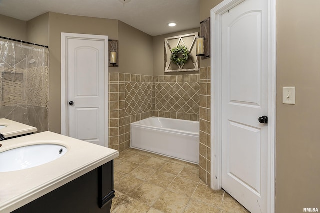 full bath with tile walls, recessed lighting, a bath, vanity, and a wainscoted wall