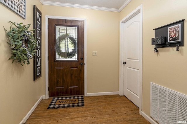entryway with visible vents, wood finished floors, baseboards, and ornamental molding