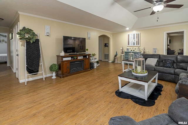living room featuring crown molding, light wood-type flooring, visible vents, ceiling fan, and arched walkways
