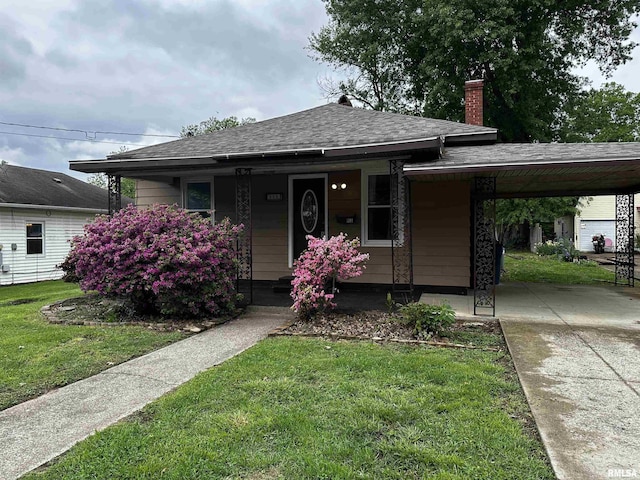view of front of property with an attached carport, a chimney, a front lawn, a porch, and roof with shingles