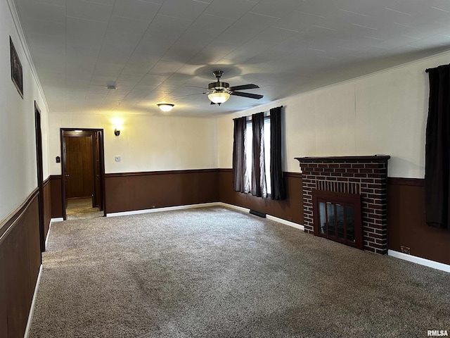 unfurnished living room with a ceiling fan, wainscoting, visible vents, a brick fireplace, and carpet floors