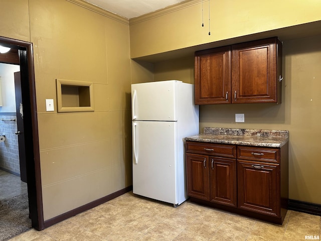 kitchen with freestanding refrigerator, dark countertops, baseboards, and ornamental molding