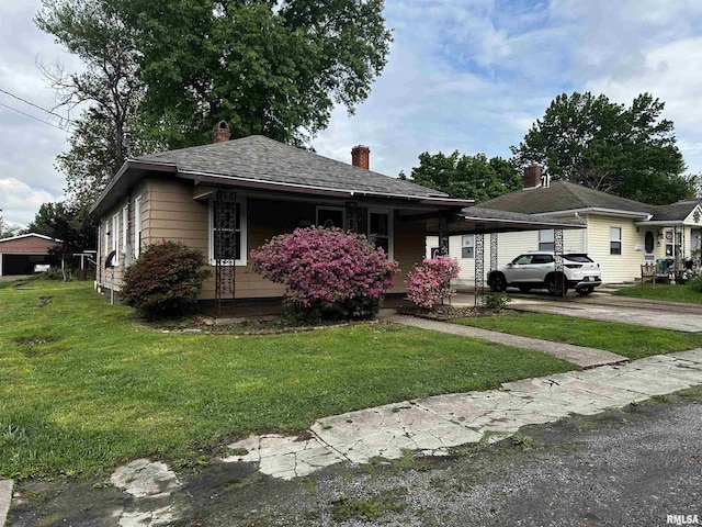 bungalow-style house featuring concrete driveway, a chimney, and a front yard