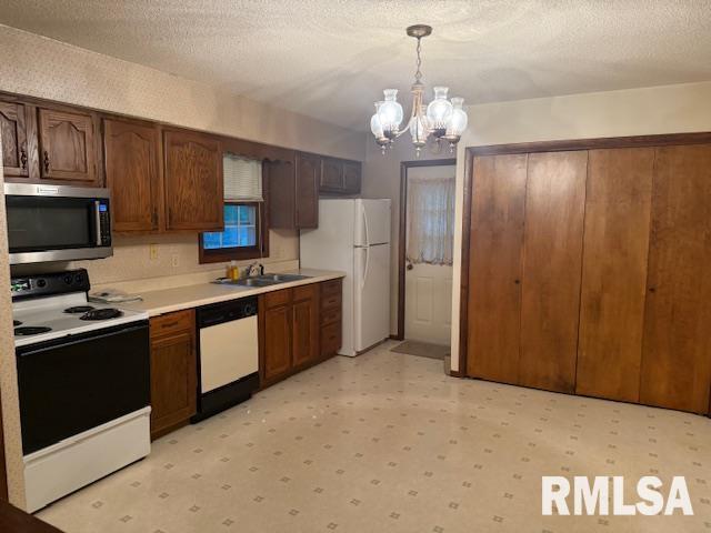 kitchen with light floors, white appliances, hanging light fixtures, an inviting chandelier, and light countertops