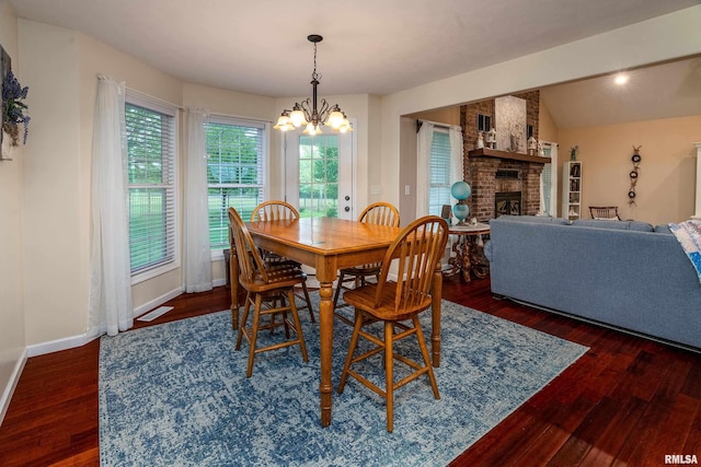 dining room featuring wood finished floors, visible vents, a fireplace, an inviting chandelier, and baseboards