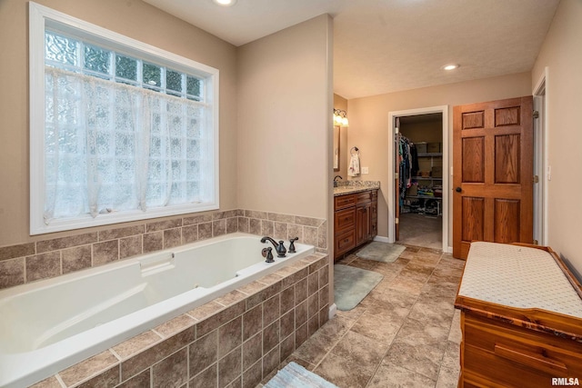 full bathroom with a walk in closet, a bath, a wealth of natural light, and vanity