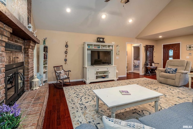 living area featuring a ceiling fan, vaulted ceiling, a fireplace, and wood finished floors