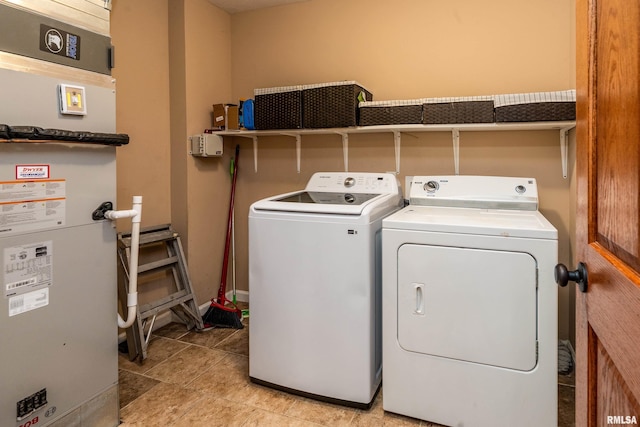 clothes washing area featuring baseboards, laundry area, heating unit, and washer and clothes dryer