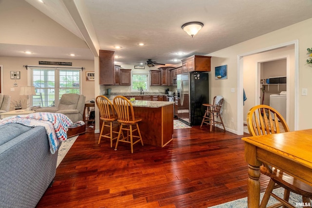 kitchen with a breakfast bar area, a sink, open floor plan, a peninsula, and appliances with stainless steel finishes