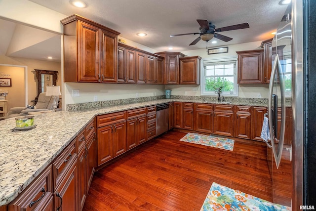 kitchen with a sink, dark wood-style flooring, light stone countertops, ceiling fan, and appliances with stainless steel finishes