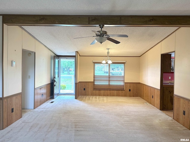 empty room featuring wooden walls, lofted ceiling with beams, and a wainscoted wall
