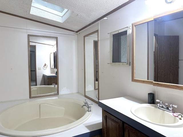 full bath with lofted ceiling with skylight, a garden tub, vanity, and a textured ceiling
