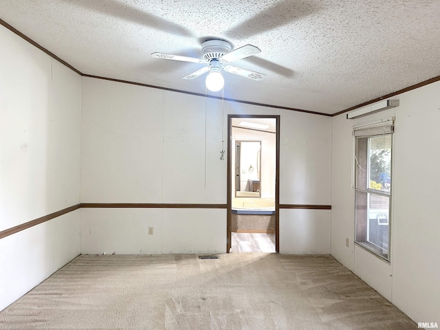 spare room featuring ornamental molding, a textured ceiling, visible vents, light carpet, and a ceiling fan