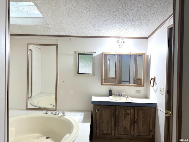 bathroom with a skylight, vanity, a textured ceiling, crown molding, and a garden tub