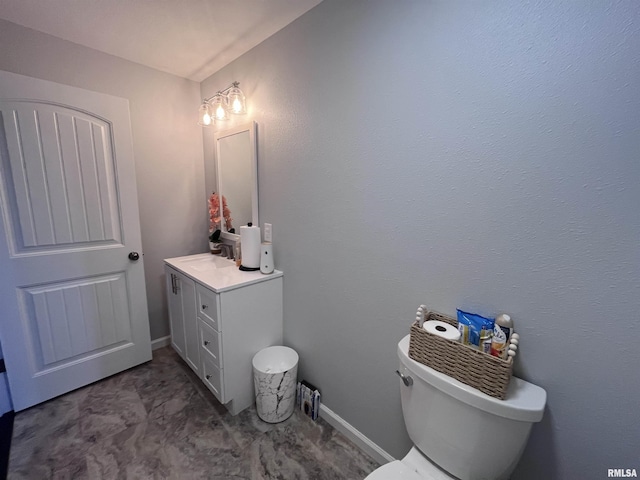 bathroom with toilet, baseboards, and vanity